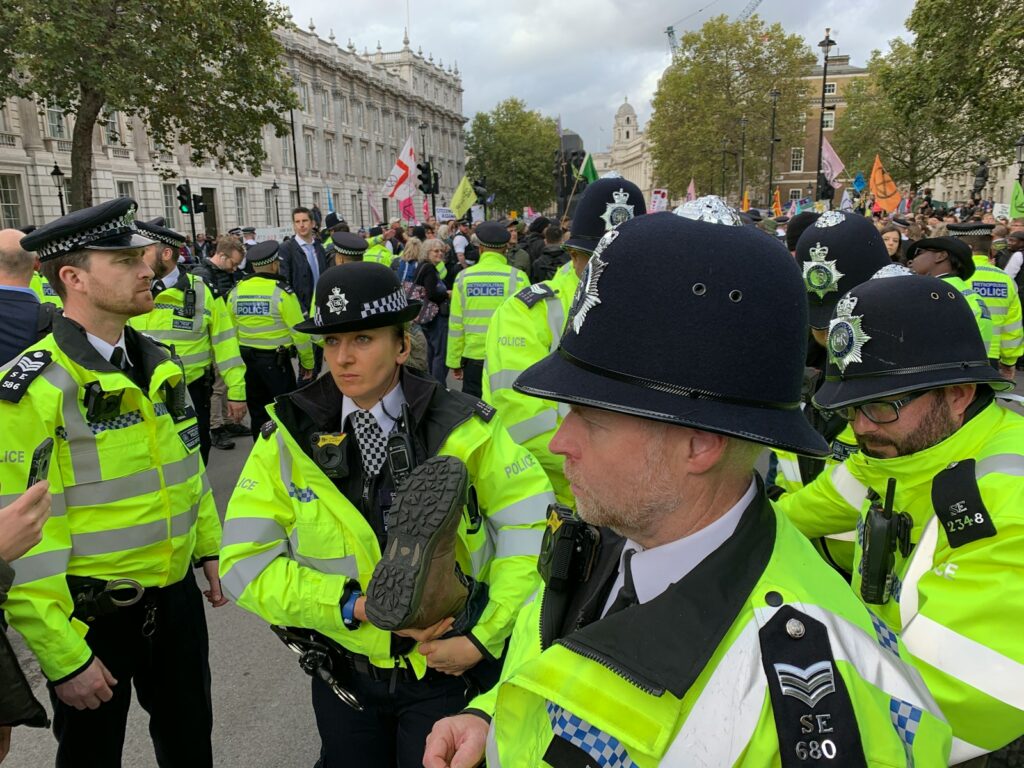 crowd of police officers near people on street beside buildings during daytime